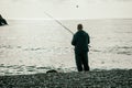 Man hobby fishing on sea tightens a fishing line reel of fish. Calm surface sea. Close-up of a fisherman hands twist Royalty Free Stock Photo