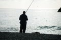 Man hobby fishing on sea tightens a fishing line reel of fish. Calm surface sea. Close-up of a fisherman hands twist Royalty Free Stock Photo