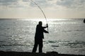 Man hobby fishing on sea tightens a fishing line reel of fish. Calm surface sea. Close-up of a fisherman hands twist Royalty Free Stock Photo