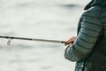 Man hobby fishing on sea tightens a fishing line reel of fish. Calm surface sea. Close-up of a fisherman hands twist Royalty Free Stock Photo