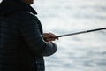 Man hobby fishing on sea tightens a fishing line reel of fish. Calm surface sea. Close-up of a fisherman hands twist Royalty Free Stock Photo