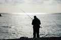 Man hobby fishing on sea tightens a fishing line reel of fish. Calm surface sea. Close-up of a fisherman hands twist Royalty Free Stock Photo