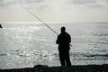 Man hobby fishing on sea tightens a fishing line reel of fish. Calm surface sea. Close-up of a fisherman hands twist Royalty Free Stock Photo