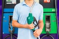 Man hold fuel nozzle to add fuel in car at gas station
