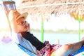 A man hold hat and sleep on hammock near the river. Royalty Free Stock Photo