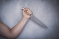 Man hold knife - aggression. Big kitchen knife in man hand. Large kitchen knife in a man`s hand, on a gray background