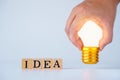 Man hold light bulb on a Wooden cubes with words `idea` on white background. concept of ideas to change perspectives, innovative