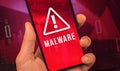 Man hold mobile phone with Malware warn screen, concept of cyber crime in the world