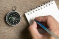 Man hold the pen to write on blank note book with compass
