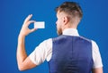 Man hold plastic blank card blue background rear view. Take this card. Banking and credit concept. Plastic bank card