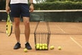 Man hold racket on clay court basket of tennis balls Royalty Free Stock Photo