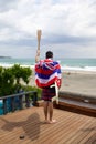 Man hold a torch used in large sporting event , with Hawaiian flag and surfboard.