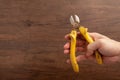 A man hold a yellow cutting plier on wooden background Royalty Free Stock Photo