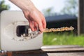 A man holding a anode damaged from corrosion. In the background the boiler and a view of the lawn. Close up