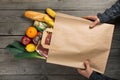 Man holding bag of different healthy food on wooden kitchen