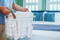 A man holding a basket of organized clean rolled white towels for guests near a bed in a guest bedroom Royalty Free Stock Photo