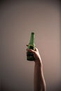 Man holding a beer bottle in his hand against a dark wall background Royalty Free Stock Photo