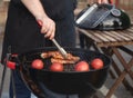 Man holding a beer grilling meat with tomatoes on a BBQ outdoors Royalty Free Stock Photo