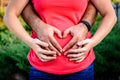 Man holding belly of his pregnant wife making heart. Pregnant woman and loving husband hugging tummy. Royalty Free Stock Photo