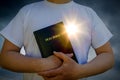 Man holding a Bible with glowing heart sun