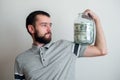 man holding big glass jar with money banknotes on hand. finance power and stability concept. moderate consumption and