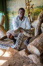 Man holding a big python with his hands showing it to tourists. PheZulu Cultural Village, South Africa