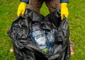 Man holding black plastic trash bag with empty plastic bottles. Royalty Free Stock Photo