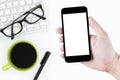 Man is holding a black smartphone with white blank mockup screen over the white desk table Royalty Free Stock Photo