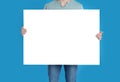 Man holding blank poster on blue background, closeup Royalty Free Stock Photo