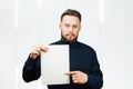 Man holding blank sheet of paper. Young guy pointing at paper sheet and looking at camera. Promotion concept Royalty Free Stock Photo