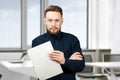 Man holding blank sheet of paper. Young guy pointing at paper sheet and looking at camera. Promotion concept Royalty Free Stock Photo