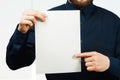 Man holding blank sheet of paper. Young guy pointing at paper sheet and looking at camera. Promotion concept Royalty Free Stock Photo