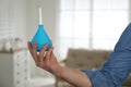 Man holding blue enema at home, closeup