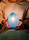 man holding blue light on two hand. magician use mineral stone predict fortune future in dark night