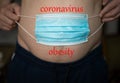 A man holding a blue medical mask over his stomach will gain weight during the pandemic of the coronavirus crisis.