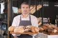 Man holding board with assortment of fresh bread in bakery Royalty Free Stock Photo