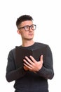 Studio shot of young handsome man holding book while thinking Royalty Free Stock Photo