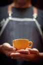 man holding with both hands orange cup of coffee. copy space