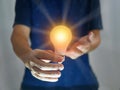 Man holding bright shining light bulb represents a new idea, thought, invention, innovation, solution, creativity, technology, and Royalty Free Stock Photo