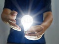 Man holding bright shining light bulb represents a new idea, thought, invention, innovation, solution, creativity, technology, and Royalty Free Stock Photo