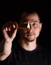 Man holding burning match stick in front of blurred face on dark background Royalty Free Stock Photo