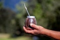 Man holding calabash yerba mate in nature. Travel and adventure concept. Latin American drink yerba mate
