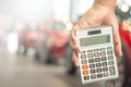 Man holding calculator for business finance on car showroom blurred bokeh background.for automotive automobile or transportation
