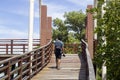 A man holding a camera walking on a wooden bridge in a mangrove forest at Stupa in the middle of river in Rayong. Royalty Free Stock Photo