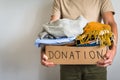 Man holding cardboard donation box full with clothes.