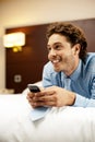 Man holding cellphone and lying on bed, relaxed Royalty Free Stock Photo
