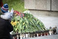 Man holding a child standing near snuffed out eternal fire covered with flowers during celebration of May 9 Victory Day