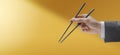 Man holding chopsticks on yellow background Royalty Free Stock Photo