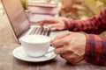 Man holding a cofffee; on table with laptop and books, vintage s Royalty Free Stock Photo