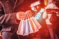 Man holding colorful shopping bags on the dark city background. Sun glare effect, orange toned Royalty Free Stock Photo